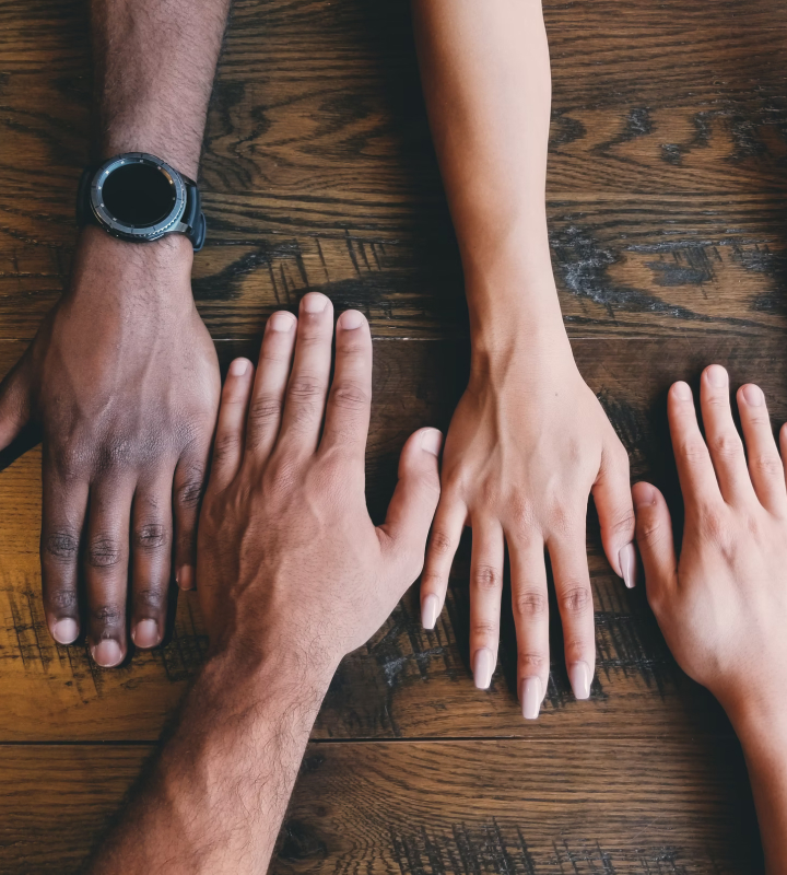 Cuatro manos diferentes de hombre y mujer alineadas sobre una mesa