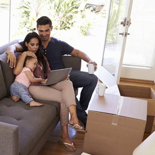 Family of three relaxing on couch while viewing a laptop.