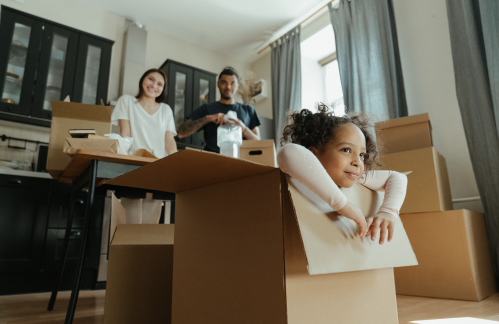 A mother, father and small girl unpacking boxes in their rented home.