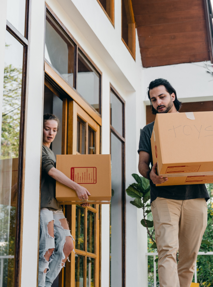 Man and women carry moving boxes out the front door of their rental unit.