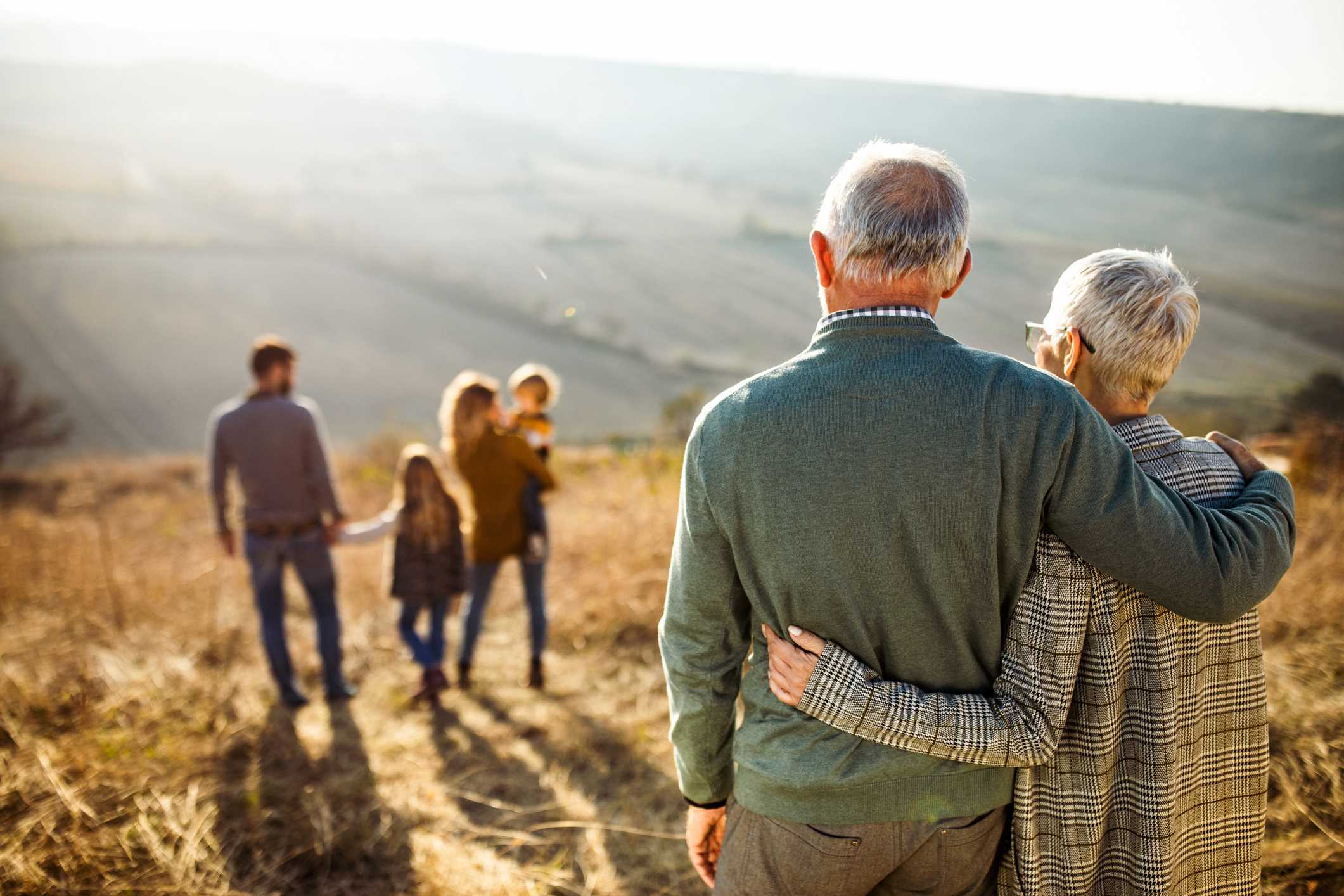 Pareja de ancianos viendo una familia joven