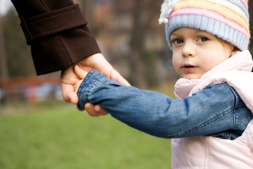 Niño pequeño cogido de la mano con un cuidador