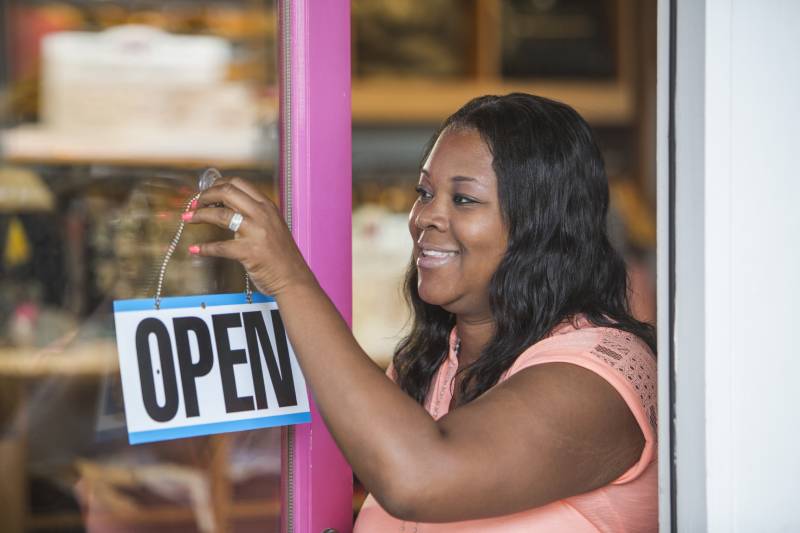 Woman hanging Open sign on business door