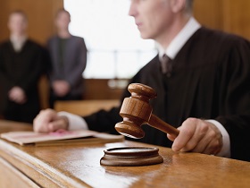 Judge using his gavel while sitting on the bench in a courtroom