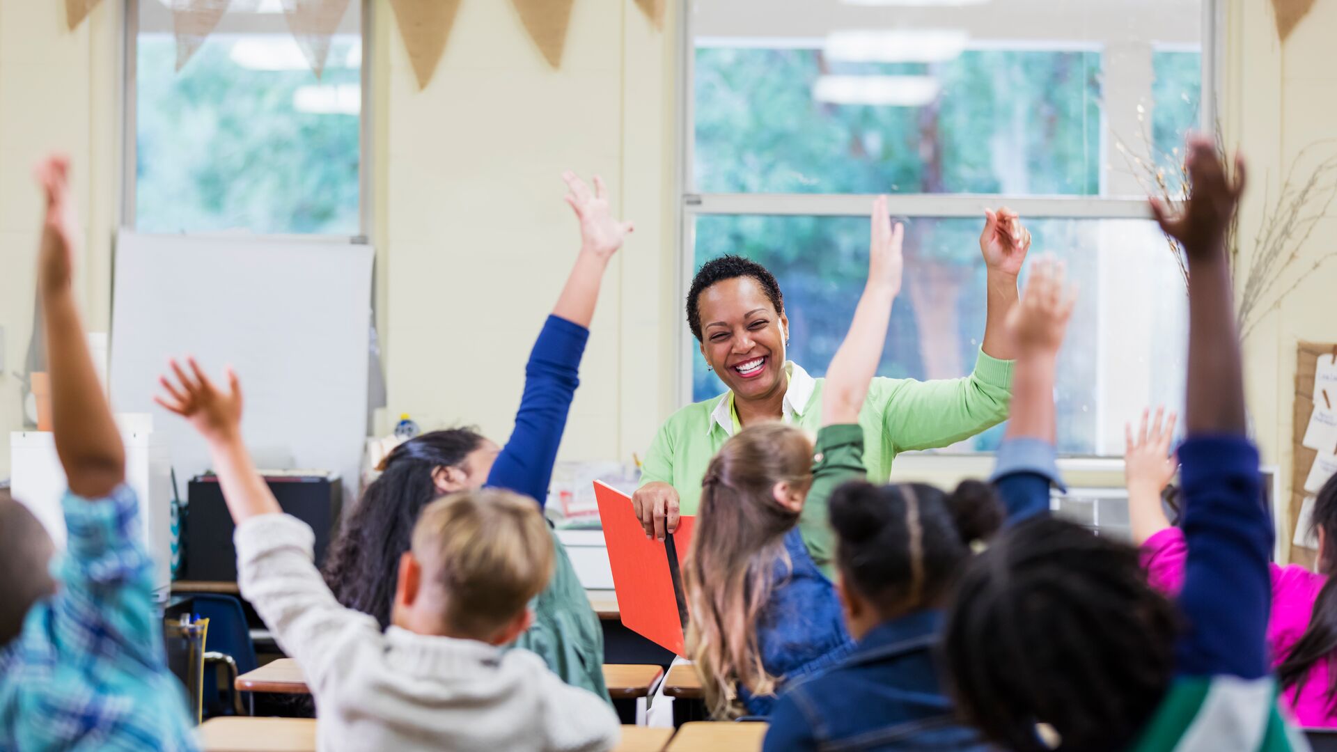 students in classroom raising hands