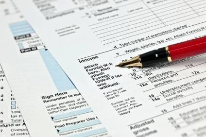 IRS tax forms on a desk with an ink pen.