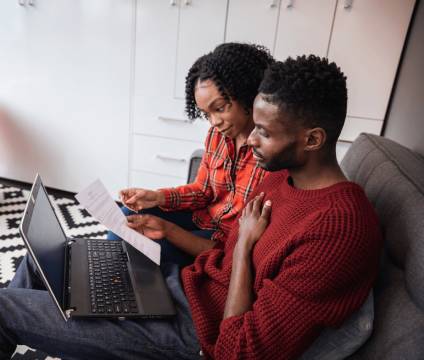 Couple sitting on couch and reviewing examples of digital real estate.