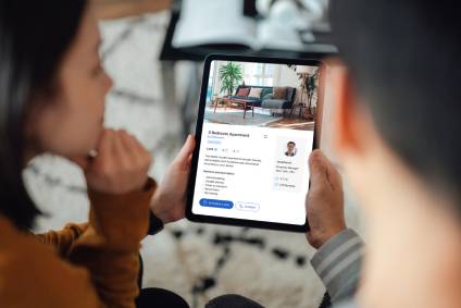 Real estate listing on a computer tablet being viewed by a man and a woman.