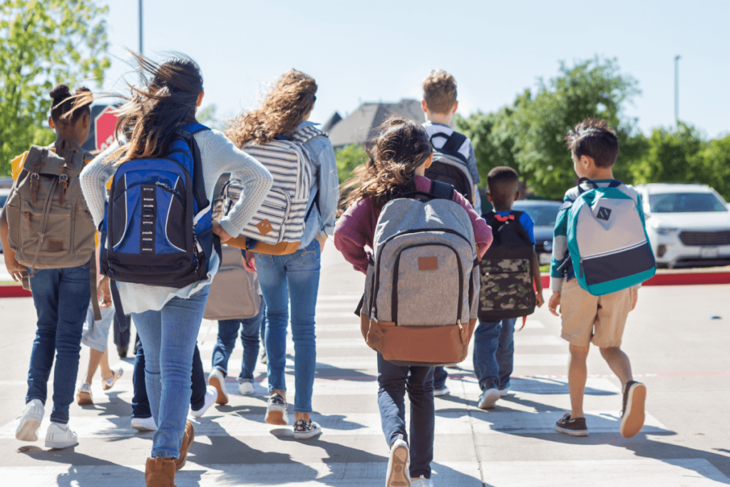 Un grupo de jóvenes escolares con mochilas caminando hacia la escuela.