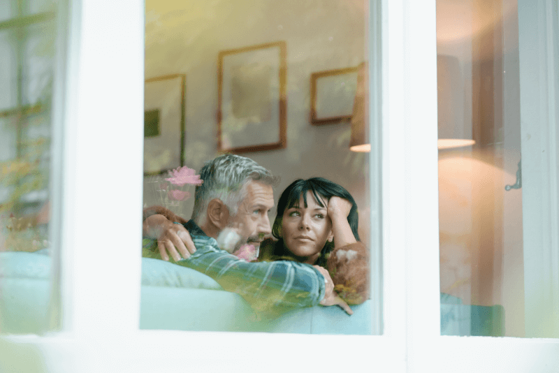 Pareja de mediana edad mirando por la ventana.