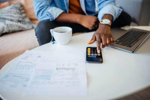 Man calculating his student loan debt and payments on a calculator.