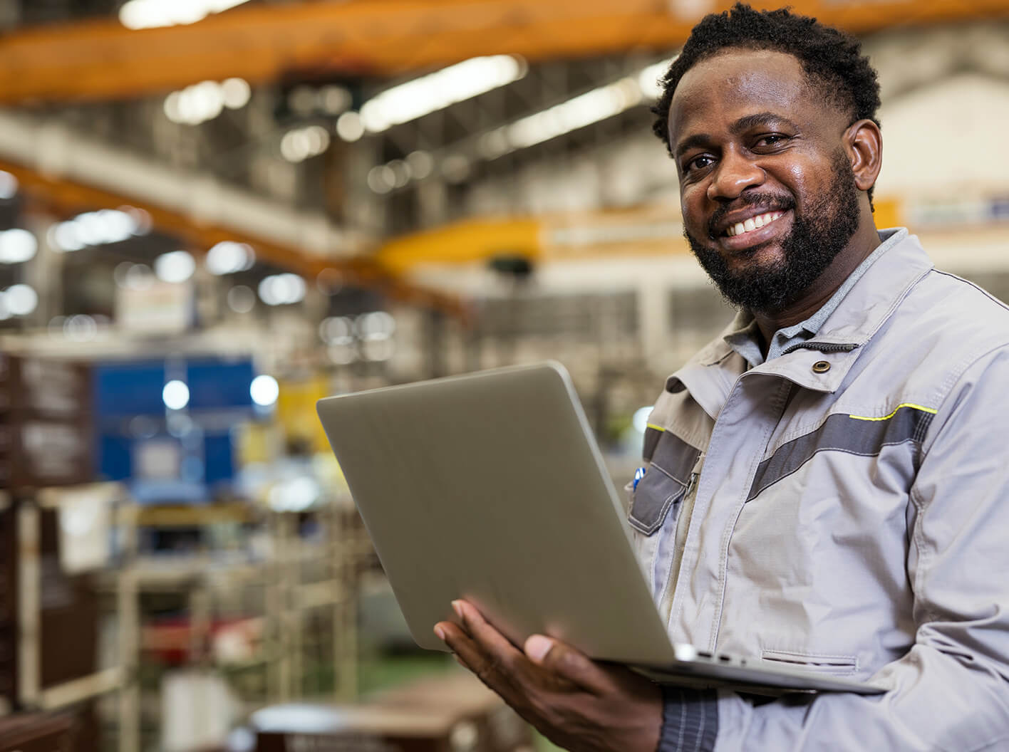 Smiling small business owner holding a laptop in his workplace.