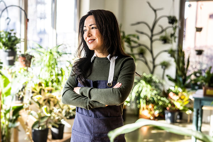 Small business owner standing in her plant shop with her arms crossed.