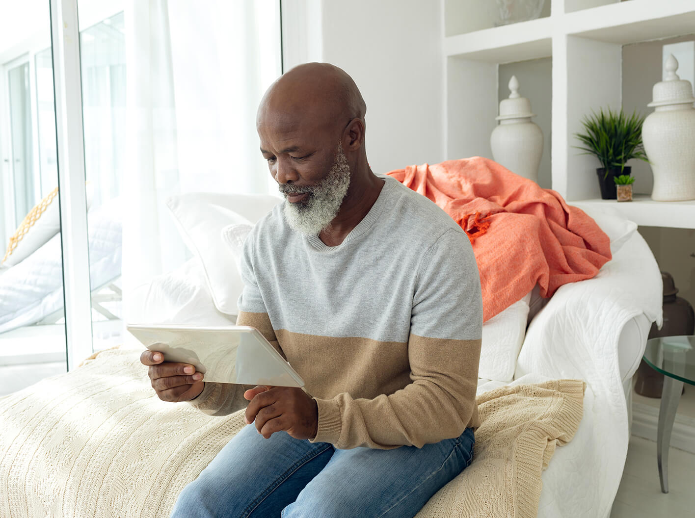 Mature man looking at a Trust document while sitting on a chair in his living room.