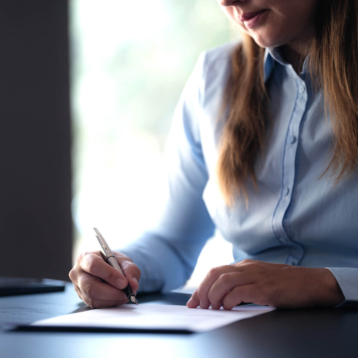 A woman is signing a document