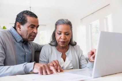 Couple looking at retirement planning documents and their laptop computer.