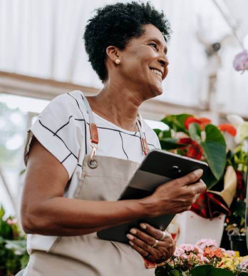 Smiling greenhouse business owner holding a computer tablet.