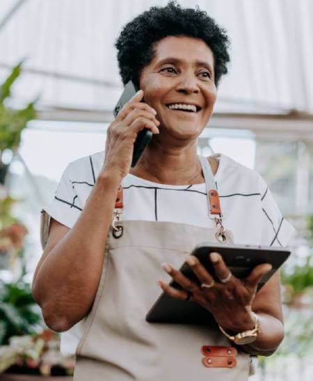 Smiling business owner learning LLC filing fees by state holding a computer tablet.