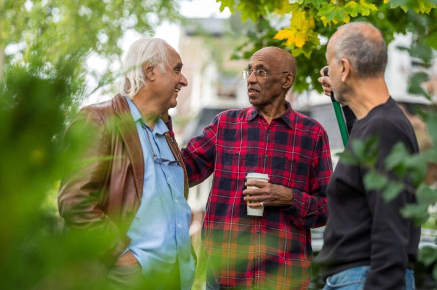 Male neighbors discussing homeownership dispute outside.