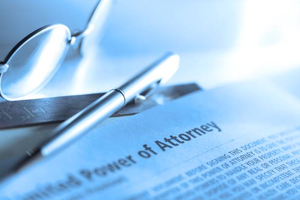 A specific type of Power of Attorney next to a pair of eyeglasses and an ink pen.