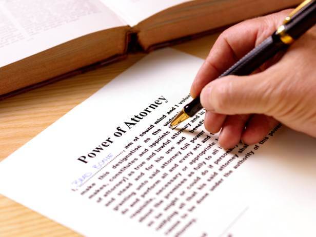 Man filling out a Power of Attorney legal document with an ink pen.